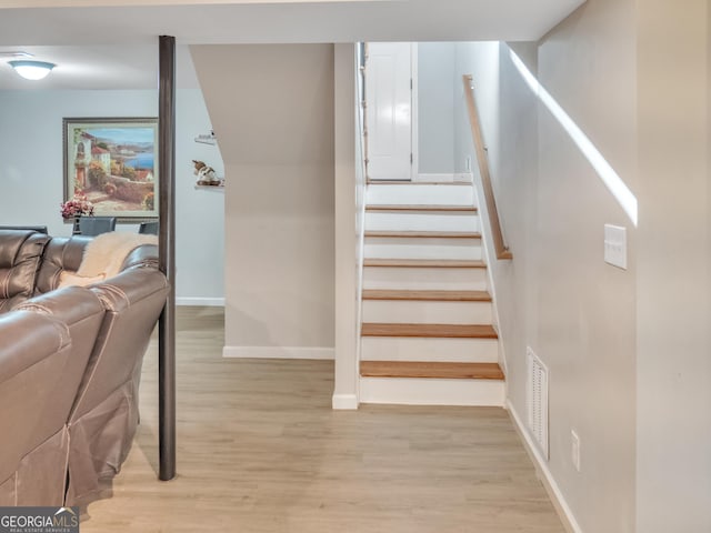 staircase with wood finished floors, visible vents, and baseboards