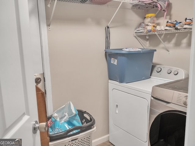 clothes washing area featuring laundry area, washer and clothes dryer, and baseboards