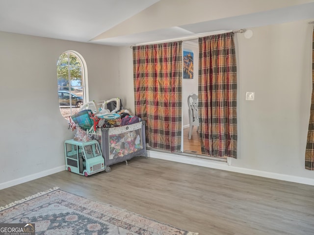 interior space featuring lofted ceiling, baseboards, and wood finished floors