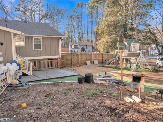 view of yard featuring fence, a playground, and a wooden deck