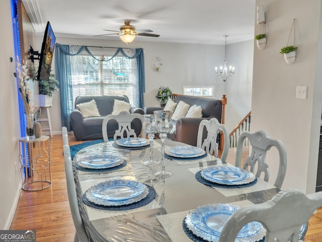 dining space with ceiling fan with notable chandelier, wood finished floors, and baseboards