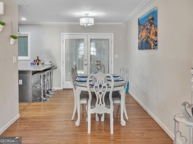 dining space with french doors, baseboards, crown molding, and light wood finished floors