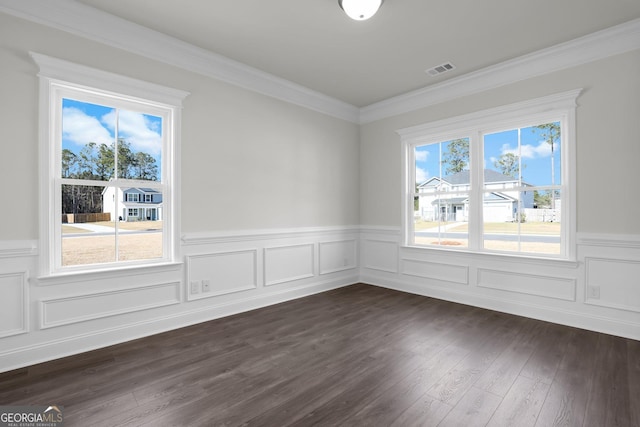 spare room with a wainscoted wall, crown molding, dark wood-style floors, and visible vents