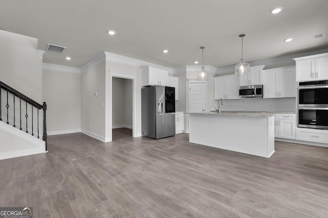 kitchen with visible vents, tasteful backsplash, wood finished floors, stainless steel appliances, and white cabinets