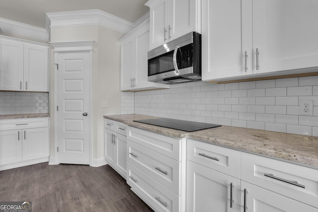 kitchen featuring stainless steel microwave, ornamental molding, dark wood-style floors, white cabinets, and black electric cooktop