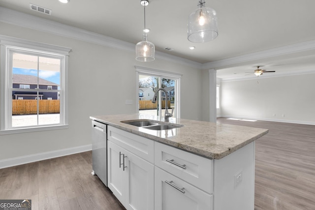 kitchen with wood finished floors, visible vents, ornamental molding, a sink, and stainless steel dishwasher