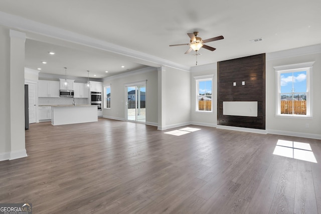 unfurnished living room featuring ornamental molding, a fireplace, baseboards, and wood finished floors