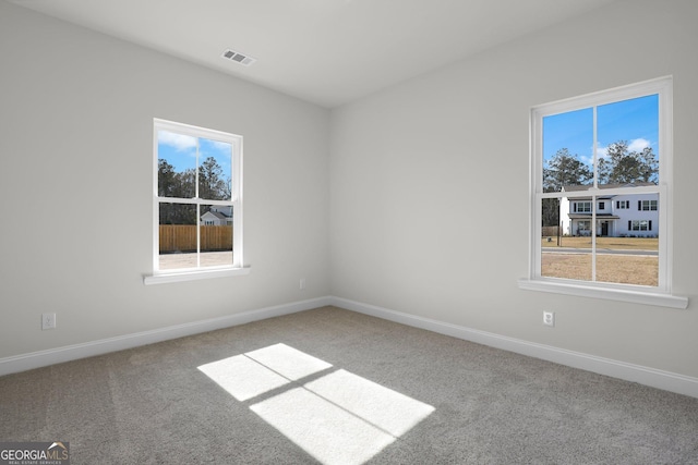 carpeted empty room with visible vents and baseboards