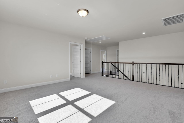 unfurnished room with baseboards, visible vents, carpet floors, and attic access