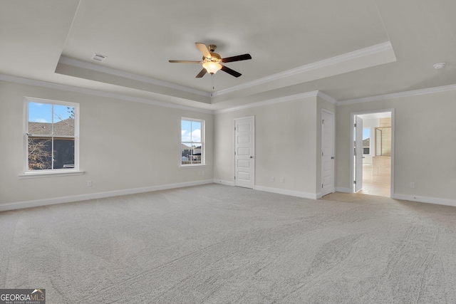 unfurnished bedroom with visible vents, baseboards, light colored carpet, a tray ceiling, and ornamental molding