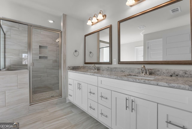 bathroom featuring double vanity, visible vents, a stall shower, and a sink