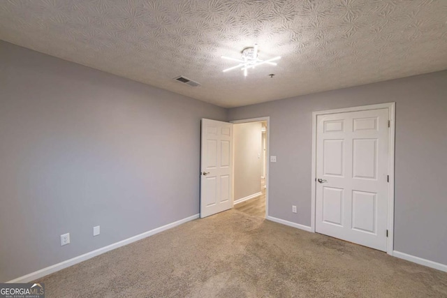 unfurnished bedroom with a textured ceiling and carpet