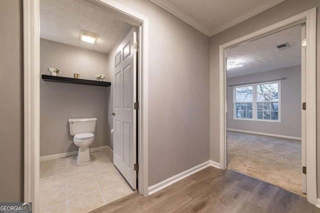 bathroom featuring wood-type flooring, crown molding, a textured ceiling, and toilet