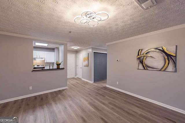 unfurnished living room with wood-type flooring, sink, a textured ceiling, and crown molding