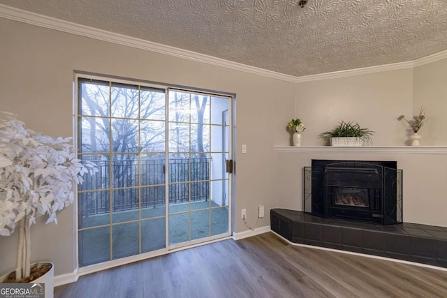 unfurnished living room with a tiled fireplace, crown molding, hardwood / wood-style flooring, and a textured ceiling