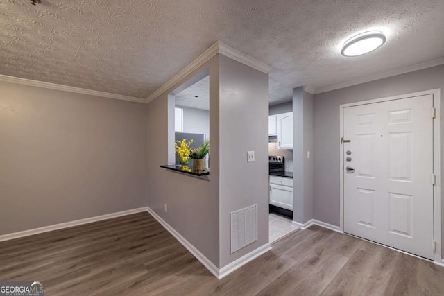 foyer featuring ornamental molding, a textured ceiling, and light hardwood / wood-style flooring