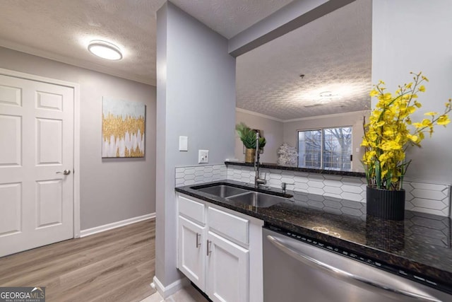 kitchen featuring sink, white cabinetry, light wood-type flooring, stainless steel dishwasher, and dark stone counters