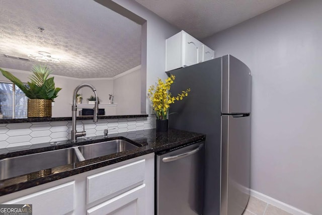 kitchen with appliances with stainless steel finishes, tasteful backsplash, sink, white cabinets, and dark stone counters