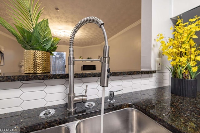 interior details with ornamental molding, sink, dark stone countertops, and backsplash