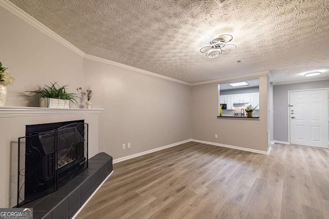 unfurnished living room with hardwood / wood-style flooring, crown molding, a textured ceiling, and a fireplace