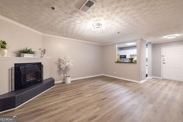 unfurnished living room with hardwood / wood-style flooring, crown molding, a tile fireplace, and a textured ceiling