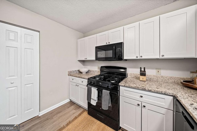 kitchen featuring white cabinets, light wood-type flooring, and black appliances