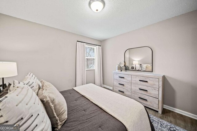 bedroom with a textured ceiling and dark hardwood / wood-style flooring