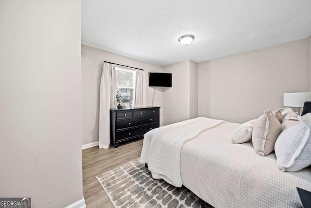 bedroom featuring a textured ceiling and light hardwood / wood-style floors