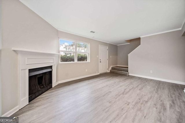 unfurnished living room featuring ornamental molding and light hardwood / wood-style flooring