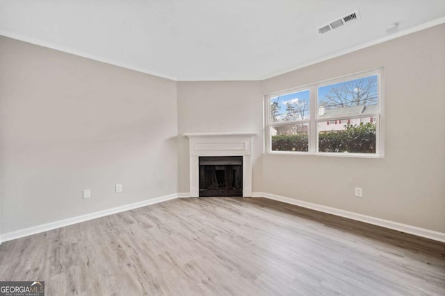 unfurnished living room featuring crown molding and light hardwood / wood-style floors