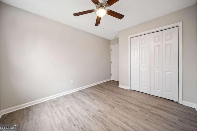 unfurnished bedroom with ceiling fan, light wood-type flooring, and a closet