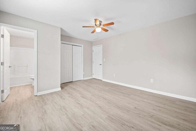 unfurnished bedroom with ensuite bathroom, a closet, ceiling fan, and light wood-type flooring