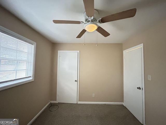 unfurnished bedroom with ceiling fan and dark carpet