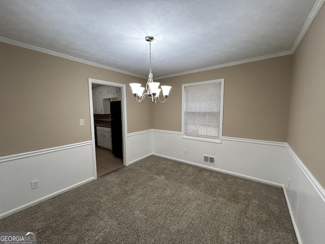 carpeted empty room featuring a notable chandelier, ornamental molding, and a textured ceiling