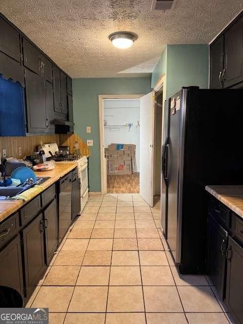 kitchen featuring light tile patterned flooring, sink, a textured ceiling, and black appliances