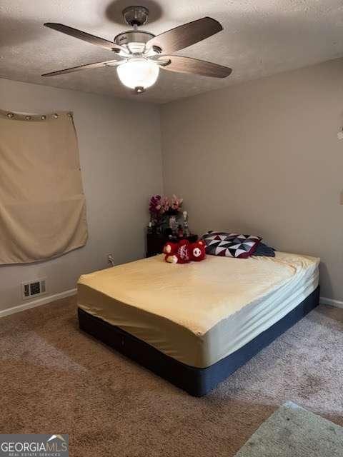 bedroom featuring ceiling fan, carpet floors, and a textured ceiling