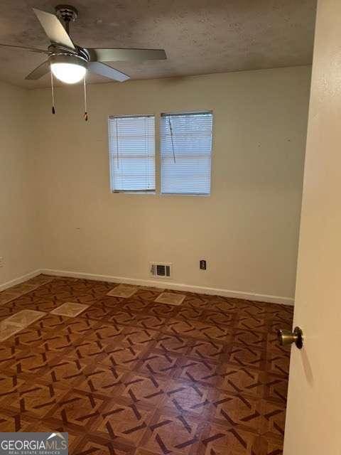 spare room featuring ceiling fan, parquet floors, and a textured ceiling