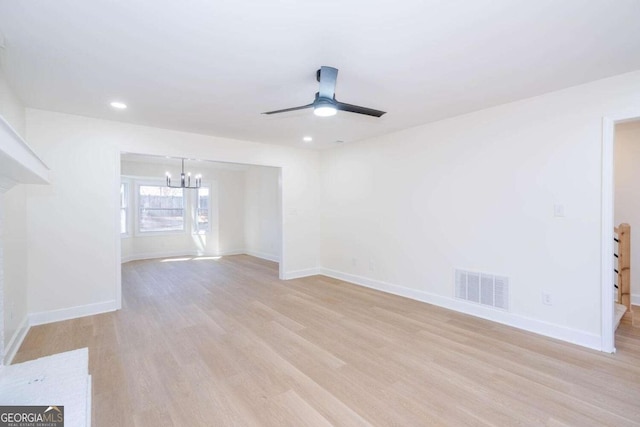 unfurnished living room with ceiling fan with notable chandelier and light hardwood / wood-style flooring