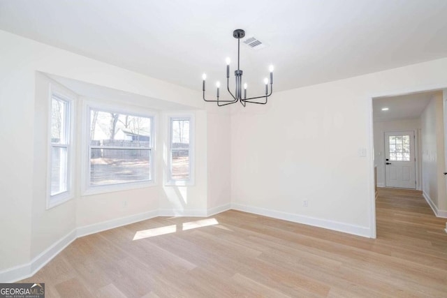 unfurnished dining area featuring light hardwood / wood-style flooring and a chandelier