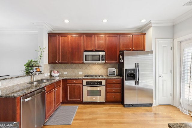 kitchen featuring sink, appliances with stainless steel finishes, decorative backsplash, dark stone counters, and light wood-type flooring