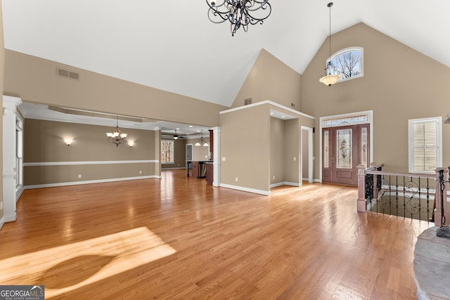 entryway featuring hardwood / wood-style flooring, ceiling fan with notable chandelier, and high vaulted ceiling