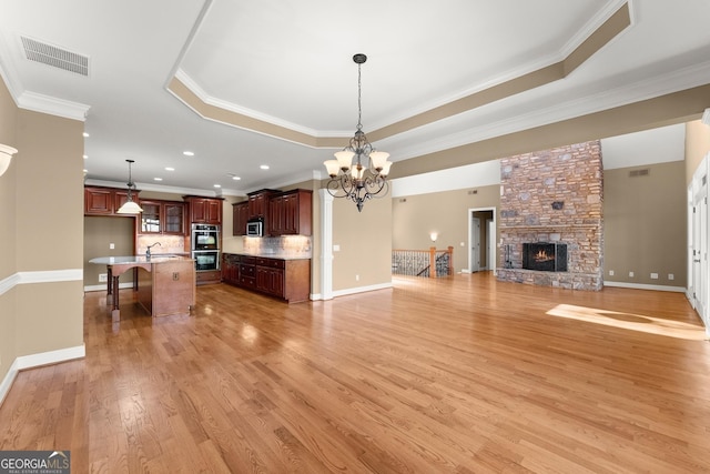 kitchen featuring a kitchen island, stainless steel appliances, a tray ceiling, a kitchen bar, and decorative light fixtures