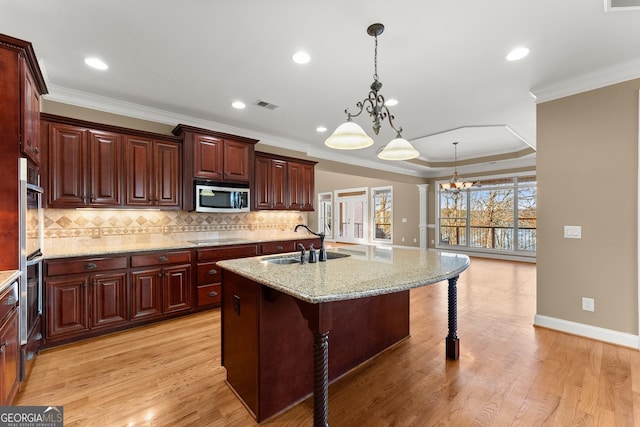 kitchen featuring a kitchen bar, light stone counters, hanging light fixtures, an island with sink, and stainless steel appliances