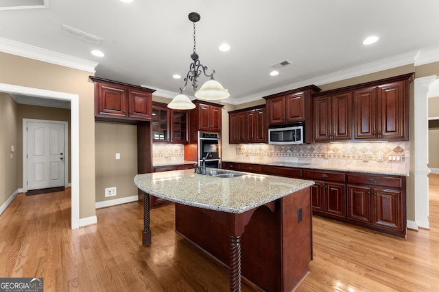 kitchen featuring appliances with stainless steel finishes, a breakfast bar, sink, a kitchen island with sink, and light stone countertops