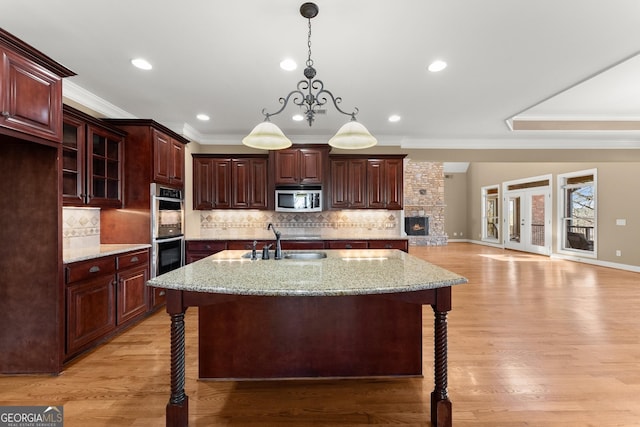 kitchen with light stone counters, stainless steel appliances, a kitchen bar, and a kitchen island with sink