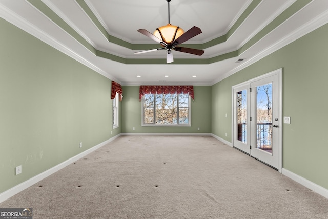 carpeted empty room featuring a raised ceiling, crown molding, and ceiling fan