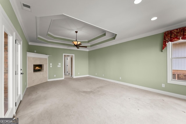 spare room featuring a premium fireplace, carpet, a wealth of natural light, and crown molding
