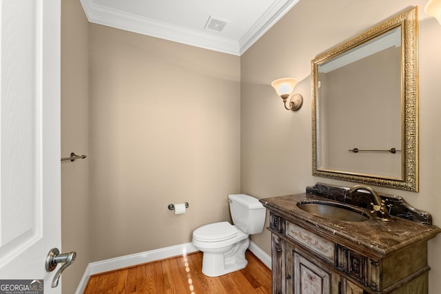 bathroom featuring ornamental molding, toilet, wood-type flooring, and vanity