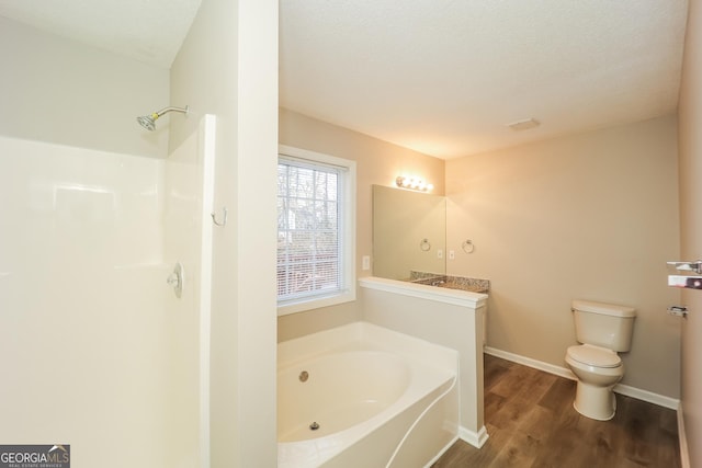 bathroom with toilet, wood-type flooring, a textured ceiling, vanity, and a bath