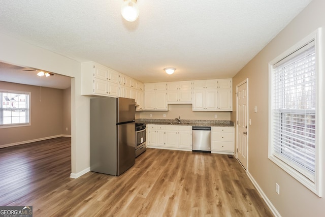 kitchen featuring sink, a textured ceiling, light hardwood / wood-style flooring, appliances with stainless steel finishes, and white cabinets